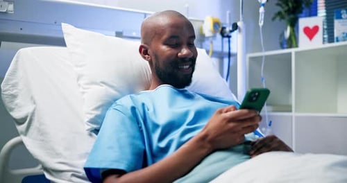 Mobile, smile and man in bed at hospital for typing message, medical update and recovery