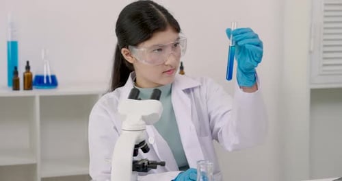 Teenage Scientist Analyzing Sample with Microscope in Lab