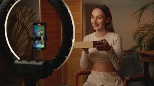 Woman Opens Cardboard Box In Front Of Phone