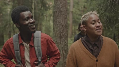 Company of Cheerful Friends Enjoying Hike in Forest