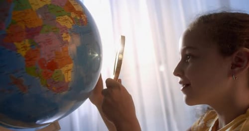 Child Exploring Globe with Magnifying Glass