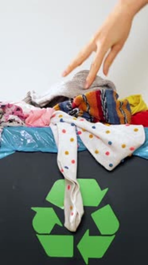 Clothes Being Placed Into Recycling Bin
