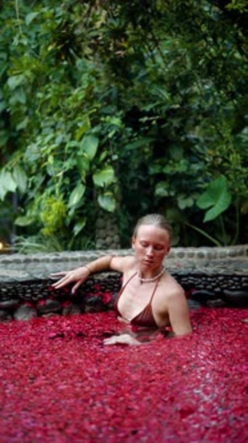 Woman Relaxing in the Pool Filled with Flowers Petals in Luxury Spa