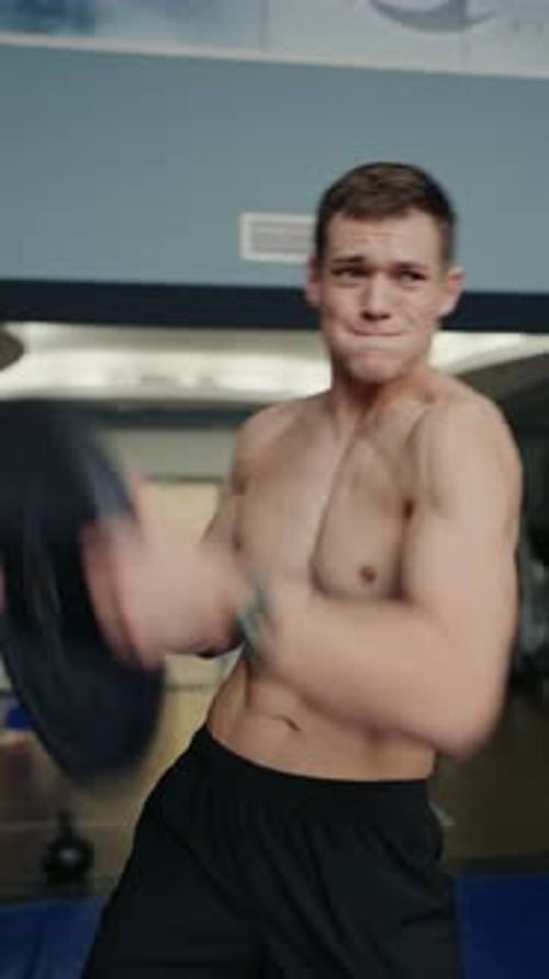 Fit Young Man in Intense Gym Workout Lifting Heavy Tire
