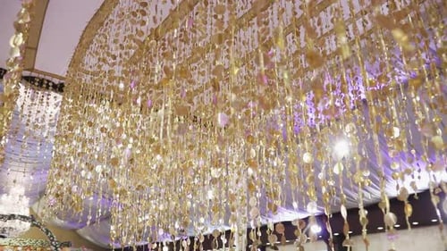An exquisite gold decoration inside a wedding hall, attached to the ceiling, is captured in a close-