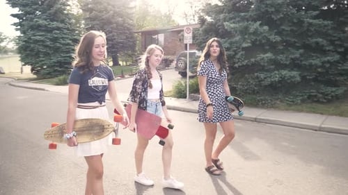 Three Friends Walk with Skateboards in Suburban Street