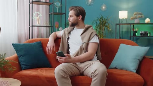Young Man Using Smartphone on Couch at Home