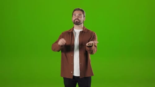 Man Standing Over Green Background and Gesturing in Air