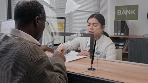 Bank Teller Helping Elderly Customer with Signing Documents in Bank Office