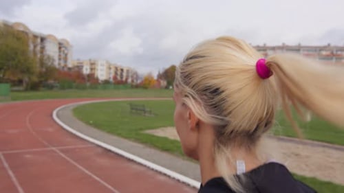 Close up of a young and sporty blonde woman running in slow motion on an athletic track