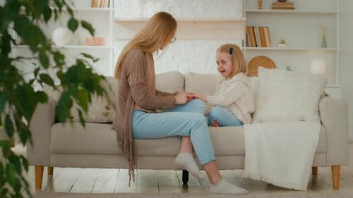 Mother and Daughter Chatting on Sofa Indoors