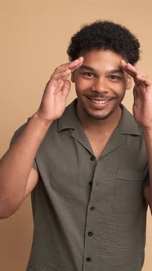 Surprise Young Man Smiling at Camera in Beige Studio