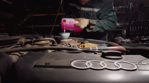 Master in car service station pours pink antifreeze into tank of Audi car