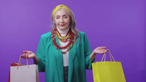 An Elderly Woman in Vibrant Attire Wearing Colorful Necklaces Against a Bold Background