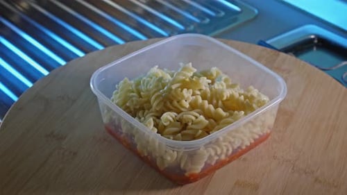 Pâtes rotini cuites dans un récipient alimentaire avec sauce épicée à la dinde et aux haricots au fond. rack focus