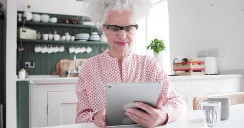 Woman Using Tablet Device at Kitchen Table