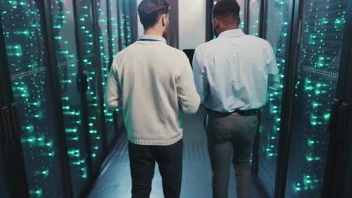 Zwei Personen erkunden einen Hightech-Serverraum und diskutieren über Daten