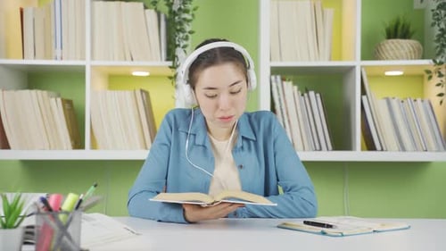 Young Woman Reads a Book at Her Desk