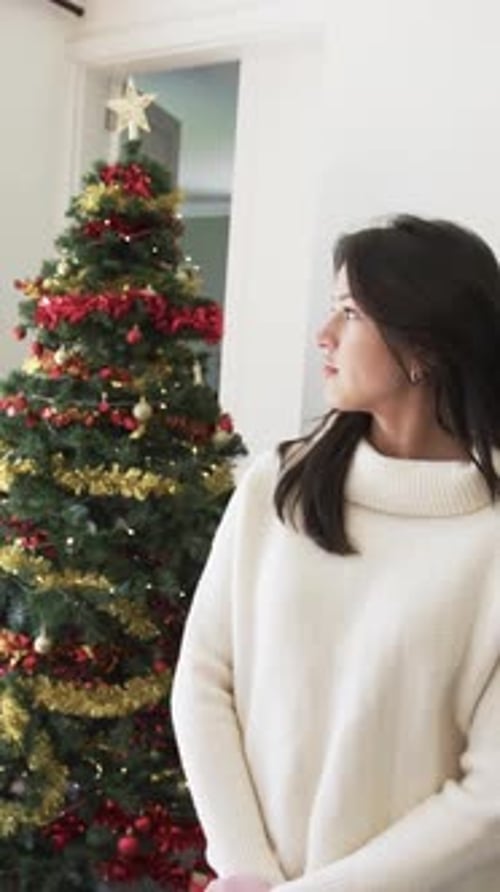 Young Woman Smiling in Front of Christmas Tree