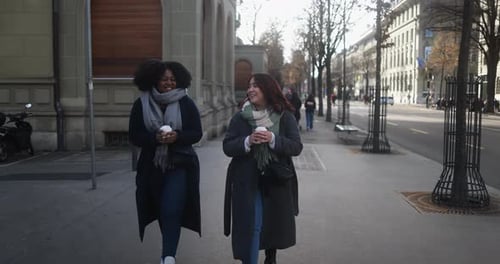 Multiracial women friends laughing together with coffee on a cold winter day in New York