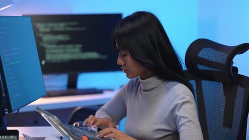 Asiatische Entwicklerin tippt Code mit Hingabe auf der Tastatur