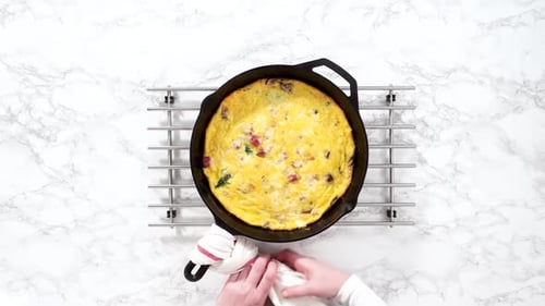 Frittata aux épinards et au jambon fraîchement cuits dans une poêle en fonte