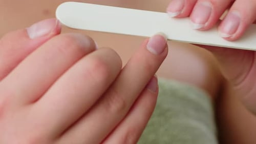 Close Up Hand View of Lady Filing Nails with Towel Wrapped Around Chest