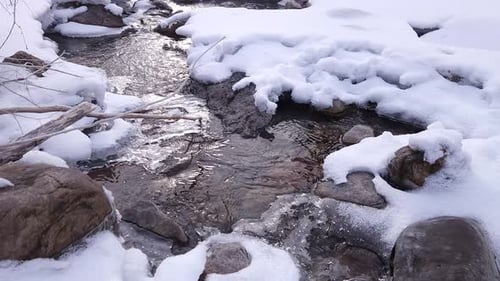 Spring Snow Melt on a Mountain Stream. An open section of a stream with melting snow and ice along