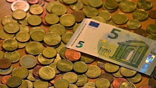 A diverse set of Euro bills fluttering onto a table covered in Euro coins, captured in a close-up sh