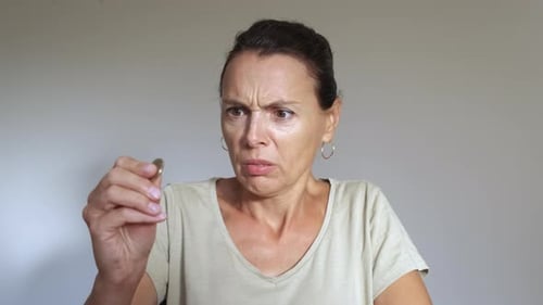 Concerned Woman Looking at a Coin Indoors