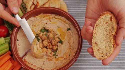 Spreading Hummus on Bread Top View Hummus Garnished with Chickpeas Olive Oil Spices and Greens Among