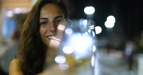 Smiling Woman Holds Wine Glass at Night