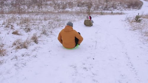 Eine Schneerutsche, auf der eine Familie Spaß auf Plastikschlitten hat Rückansicht