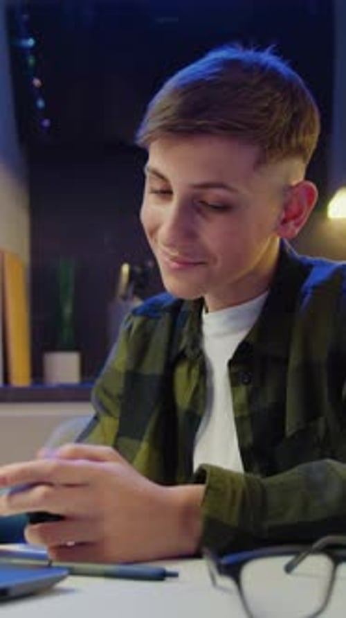 Teen Boy Plays Video Game on Mobile Phone Indoors
