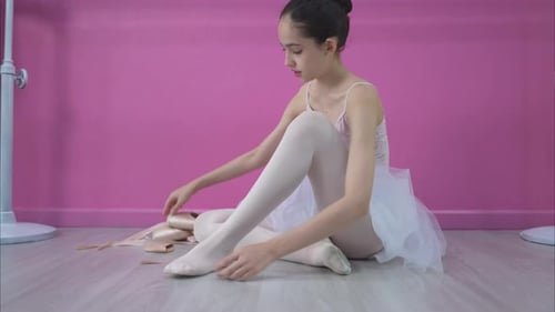 Teen Ballerina Putting on Pointe Shoes in Studio