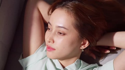 Woman Relaxing Indoors on Couch in Sunlight