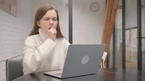 Young Woman Coughs while Working on Laptop
