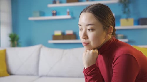 Young Woman Looking Thoughtful on Couch Indoors