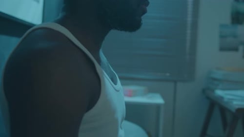 Man in Tank Top in Dimly Lit Room