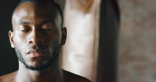 Zeitlupe eines jungen afrikanischen, verschwitzten und muskulösen Mannes während des Trainings, der in die Kamera lächelt.