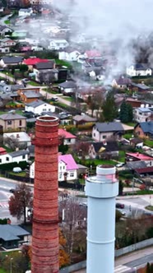 Manufacturing plant smoke stack pollution in city near homes, vertical