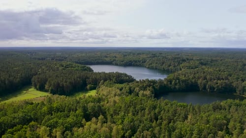 Aerial rising view overlooking vast back country woodland wilderness and lake