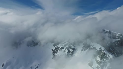 Aerial View of Snowy Mountains and Clouds