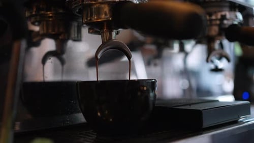 4K Close up of coffee maker machine pouring espresso shot into coffee cup.