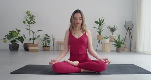 Blonde Caucasian Woman in Lotus Pose Meditating in a Yoga Studio