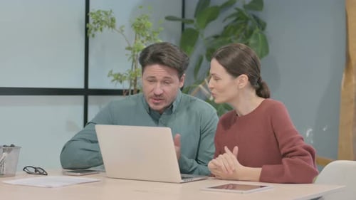 Colleagues Collaborate on Laptop in Modern Office