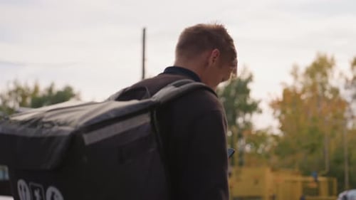 Delivery Man Walking Man Navigating Residential Street During Autumn Evening Male Delivery Worker