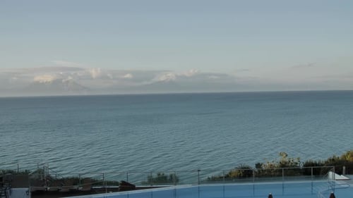 Wide Panning shot of a coast view from the beautiful swimming pool to deep-sea with some mountains i