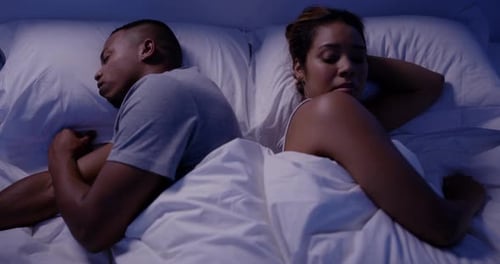 4k video footage of a young beautiful wife irritated by her handsome husbands snoring in bed at home