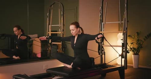 Woman Doing Pilates Exercise on Reformer in Studio